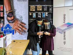Iranian women, wearing personal protective equipment, look at a cell phone at a shop in Mashhad on April 11, 2020, amid the coronavirus (COVID-19) pandemic.  AFP/File