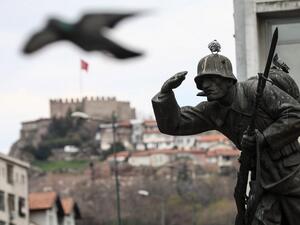 A pigeon flies next to a statue of a soldier on Ulus square, with the Ankara Castle in the background, in Ankara, on April 11, 2020, during the 48-hour curfew imposed by the government to stem the spread of the novel coronavirus (COVID-19).  Adem ALTAN / AFP