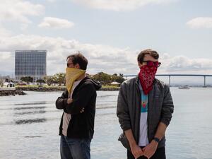 Two men wearing bandanas to protect their face against the COVID-19, Coronavirus outbreak wait for their order at the Tuna Harbor Dockside Market in San Diego, California on April 11, 2020. Due to the Covid-19, Coronavirus pandemic, fisherman had to regroup to stay afloat and lower their cost for the locals who have been purchasing their fish since local restaurants have been shut down. ARIANA DREHSLER / AFP