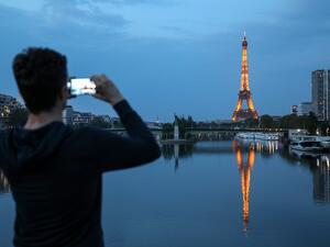 A man takes pictures of the Eiffel tower and its reflection on the Seine river, in Paris, on April 12, 2020, on the 27th day of a strict lockdown aimed at curbing the spread of the COVID-19 pandemic, caused by the novel coronavirus. Ludovic MARIN / AFP