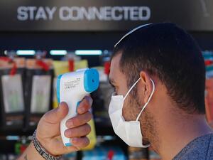 A worker checks the body temperature of a costumer before allowing him to enter the Electro Slil hardware store in Jerusalem during the COVID-19 pandemic, on April 20, 2020. Israel today allowed a reopening of high street shops, schools for children with special educational needs and a resumption of small-scale prayer meetings. EMMANUEL DUNAND / AFP