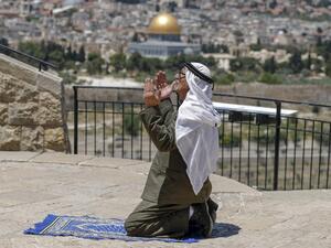 An elderly Palestinian man performs the Friday prayer during the Muslim holy month of Ramadan, at the Mount of Olives with a backdrop of the Old City of Jerusalem and the closed al-Aqsa Mosque compound, on May 8, 2020, amid the novel coronavirus pandemic crisis. AHMAD GHARABLI / AFP