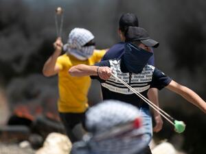 Tires burn as Palestinian youths use sling shots to hurl rocks at Israeli troops, during clashes with them in the West-Bank village of Kfar Qaddum, following a weekly demonstration against the expropriation of Palestinian land by Israel, on May 8, 2020. JAAFAR ASHTIYEH / AFP