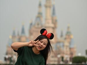 A woman gestures while visiting the Disneyland amusement park in Shanghai on May 11, 2020. Disneyland Shanghai reopened on May 11 to the public after being closed since January due to the COVID-19 coronavirus outbreak. Hector RETAMAL / AFP