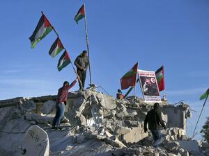 Palestinian men place a picture of Palestinian assailant Qassam Barghouti on the rublle of his family house after it was partially demolished by Israeli forces in the village of Kobar, near Ramallah, in the Israeli-occupied West Bank on May 11, 2020. Israeli forces demolished the home of a Palestinian accused of involvement in a bomb attack last year that killed an Israeli teenager in the occupied West Bank. The explosion on August 23, 2019, near a spring close to the Jewish settlement of Dolev, killed 17-y