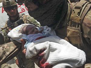 An Afghan security personnel carries a newborn baby from a hospital, at the site of an attack in Kabul on May 12, 2020. Gunmen stormed a hospital on May 12 in an ongoing attack in the Afghan capital Kabul, a government official and a fleeing doctor said. STR / AFP