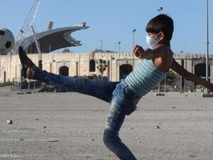 A mask-clad boy kicks a ball in front of the Camille Chamoun Sports City Stadium in the Lebanese capital Beirut amid the ongoing COVID-19 pandemic, on May 11, 2020. Lebanon ordered a four-day-long lockdown to stem the spread of the coronavirus after recording an uptick in infections in recent days amid eased restrictions. AFP