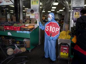 A worker wearing a full body suit holds a STOP sign in front of a Food market as he manages the flow of the customers on May 18, 2020 in the Jackson Heights neighbourhood of Queens in New York City. Johannes EISELE / AFP