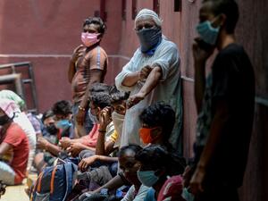 Migrant workers and families gather in front of a police station to get transferred to a railway station to board a special train to Bihar state after the government eased a nationwide lockdown imposed as a preventive measure against the COVID-19 coronavirus, in Chennai on May 27, 2020. Arun SANKAR / AFP