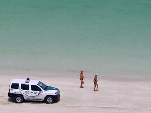 Bathers stare at a police car patroling a public beach at the Jumeirah Beach Residence in the Gulf city of Dubai on May 25, 2020. GIUSEPPE CACACE / AFP