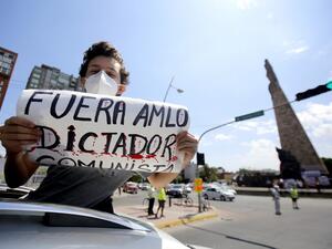 A demonstrator displays a sign reading "AMLO Out. Communist Dictator" during a caravan to protest against the government of Mexican President Andres Manuel Lopez Obrador (ALMO) and his handling of the COVID-19 novel coronavirus pandemic, in Guadalajara, Jalisco State, Mexico, on May 30, 2020. Ulises Ruiz / AFP