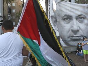 A protester carries the Palestinian flag during a demonstration in Tel Aviv's Rabin Square on June 6, 2020, to denounce Israel's plan to annex parts of the occupied West Bank. Israeli Prime Minister Benjamin Netanyahu has vowed to forge ahead with annexing settlements and the Jordan Valley, in line with the peace proposals unveiled in January by US President Donald Trump. The plan has been angrily rejected by the Palestinians, who say they were not consulted on proposals they see as capitulating to Israeli 