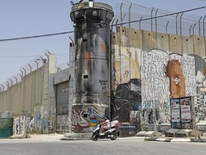 A Palestinian man rides his motorcycle past a mural painting of US President Donald Trump on Israel's controversial separation barrier in the West Bank city of Bethlehem on June 8, 2020. AHMAD GHARABLI / AFP