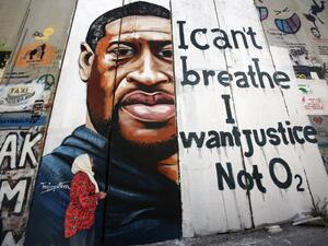 A woman looks at a mural showing the face of George Floyd, an unarmed black man who died after a white policeman knelt on his neck during an arrest in the US, painted on a section of Israel's controversial separation barrier in the city of Bethlehem in the occupied West Bank on June 10, 2020, with text reading "I can't breathe, I want justice not O2". Musa Al SHAER / AFP
