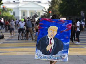 A demonstrator walks holding an anti-Trump painting on Black Lives Matter Plaza near the White House, to protest police brutality and racism, on June 10, 2020 in Washington, DC. Demonstrations are being held across the US following the death of George Floyd on May 25, 2020, while being arrested in Minneapolis, Minnesota. Jose Luis Magana / AFP