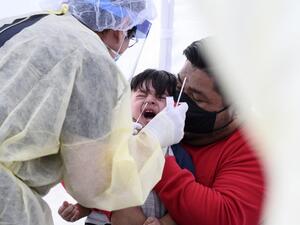 In this file photo Jose Vatres (R) holds his son Aidin who reacts as nurse practitioner Alexander Panis (L) takes a nasal swab sample to test for COVID-19 at a mobile testing station in a public school parking area in Compton, California, just south of Los Angeles, on April 28, 2020. June 10, 2020 the number of confirmed coronavirus infections in the United States topped two million according to a tally by Johns Hopkins University. The pandemic has claimed the lives of more than 112,900 people in the United