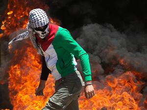 A Palestinian protester walks near burning tires during clashes with Israeli forces during a demonstration in the village of Kfar Qaddum in the Israeli-occupied West Bank, against the Jewish state's plans to annex part of the territory, on June 12, 2020. Israel intends to annex West Bank settlements and the Jordan Valley, as proposed by US President Donald Trump, with initial steps slated to begin from July 1. JAAFAR ASHTIYEH / AFP