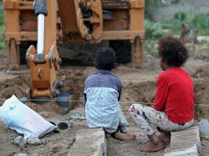 Yemeni children watch as an excavator digs graves at a specific plot for COVID-19 victims, at a cemetery in Yemen's third city of Taez, on June 14, 2020. Ahmad AL-BASHA / AFP