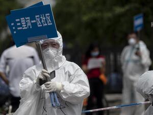 Medical staff in full protective gear carry signs to assist people who live near or who have visited the Xinfadi Market, a wholesale food market where a new COVID-19 coronavirus cluster has emerged, as they arrive for testing in Beijing on June 17, 2020. Beijing's airports cancelled two-thirds of all flights and schools in the Chinese capital were closed again on June 17 as authorities rushed to contain a new coronavirus outbreak linked to the Xinfadi wholesale food market. NOEL CELIS / AFP