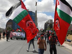 Palestinian demonstrators carry flags during a protest against Israel's plan to annex parts of the occupied West Bank, near the city of Ramallah, on June 19, 2020. Israel intends to annex West Bank settlements and the Jordan Valley, as proposed by US President Donald Trump, with initial steps slated to begin from July 1. ABBAS MOMANI / AFP