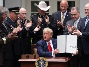 Surrounded by members of law enforcement, U.S. President Donald Trump holds up an executive order he signed on Safe Policing for Safe Communities during an event in the Rose Garden at the White House June 16, 2020 in Washington, DC. President Trump signed an executive order on police reform amid the growing calls after the death of George Floyd. Alex Wong/Getty Images/AFP ALEX WONG / GETTY IMAGES NORTH AMERICA / Getty Images via AFP