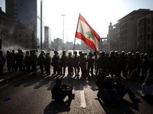 Lebanese protesters wave the national flag in front of riot police in Beirut /AFP