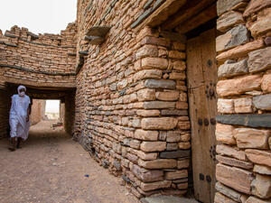 White dressed Beduin in front of historic bricked houses at world hertiage site Tichitt, Mauritania  (Shutterstock)