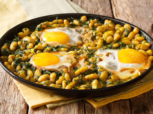 Traditional Iranian cuisine Baghali Ghatogh beans and dill with fried eggs, garlic and turmeric close-up in a frying pan on a table  (Shutterstock)	