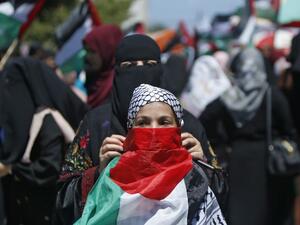 A Palestinian woman fastens a national flag as a mask on the face of a girl during a demonstration against Israel's West Bank annexation plans in Gaza City on July 1, 2020. Expectations of a major Israeli announcement on controversial annexations in the occupied West Bank dimmed, as global criticism of the project mounted and Palestinian protesters began gathering in Gaza. Mohammed ABED / AFP