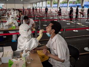 This file photo taken on June 24, 2020 shows a health worker (L, front) wearing a protective suit, face mask and face shield takes a swab test on a man at an outdoor area during a mass testing for the COVID-19 coronavirus at the Jinrong Street testing site in Beijing.NICOLAS ASFOURI / AFP