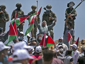 Demonstrators, clad in masks and latex gloves, wave Palestinian flags while Israeli forces stand on guard nearby during a protest against Jewish settlements and Israel's planned annexation of parts of the Israeli-occupied West Bank, in the town of Asira Shamaliya near the West Bank city of Nablus on July 10, 2020. ABBAS MOMANI / AFP
