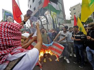 Protesters holding up the flags of the (L to R) Marxist-Leninist Popular Democratic Party, Palestine, and Lebanese Shiite movement Hezbollah burn a make-shift US flag and prints depicting US dollar bills, during an anti-US demonstration near the United States' Embassy headquarters in Awkar, northeast of Lebanon's capital Beirut on July 10, 2020. JOSEPH EID / AFP