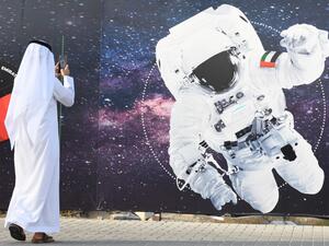 In this file photo taken on September 25, 2019 a man takes a picture of an illustration depicting an astronaut with the Emirati national flag outside Mohammed Bin Rashid Space Centre (MBRSC) in Dubai, ahead of the launching of Soyuz MS-15 spacecraft from Baikonur Cosmodrome in Kazakhstan. Hazzaa al-Mansoori, 35, who will spend eight days on the ISS, will make history by becoming the first Arab on the International Space Station but not the first Muslim. KARIM SAHIB / AFP