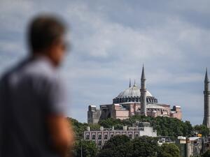 A man stays near the shore of Bosphorus at Karakoy district on July 14, 2020 as Hagia Sophia is seen in the backround in Istanbul. Turkey's Hagia Sophia could open to visitors outside prayer times and its Christian icons will remain, religious officials said on Tuesday, after a court ruling paved the way for it to become a mosque. Ozan KOSE / AFP