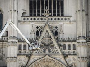 Lifted on a crane, firefighters are at work at the Cathedral of St Peter and St Paul in Nantes on July 18, 2020 after a fire ravaged parts of the gothic building before being brought under control, sparking an arson investigation and leaving Catholic officials lamenting the loss of priceless historical artefacts. The cathedral's 17th century organ was destroyed and its platform was in danger of collapsing, said regional fire chief, but added the damage was not comparable to last year's devastating blaze at 