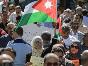 A woman raises a Jordanian national flag as she stands amidst public school teachers demonstrating and demanding pay raises, at the Professional Associations Complex in Jordan's capital Amman on October 3, 2019. (File/AFP)
