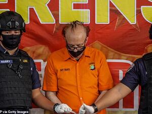 Indonesia police wearing  face masks and protective gloves guard the Frenchman Francois Abello Camille during a press conference in Jakarta. (AFP)