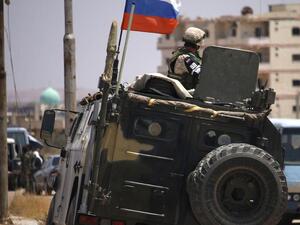 A Russian soldier on his armoured vehicle watches Syrian rebels during evacuation from Deraa city, on July 15, 2018. AFP