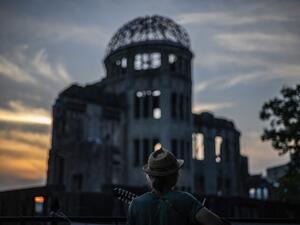 A man plays his guitar in front of in front of ruins of the Hiroshima Prefectural Industrial Promotion Hall, now commonly known as the atomic bomb dome, during sunset in Hiroshima on August 5, 2020. Japan on August 6, 2020 will mark 75 years since the world's first atomic bomb attack, with the COVID-19 coronavirus pandemic forcing a scaling back of annual ceremonies to commemorate the victims. Philip FONG / AFP