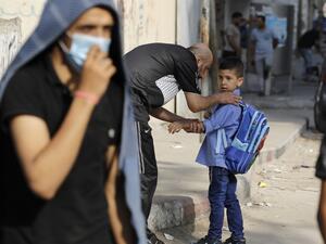 A Palestinian father picks up his son from a school run by the United Nations Relief and Works Agency (UNRWA) in Gaza City on August 13, 2020. MOHAMMED ABED / AFP