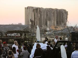 People gather in front of the devastated port of Beirut as a car carrying a statue of the Virgin Mary drives during a procession marking the day of the Assumption on August 15, 2020, more than a week after a massive chemical explosion disfigured the Lebanese capital. STR / AFP