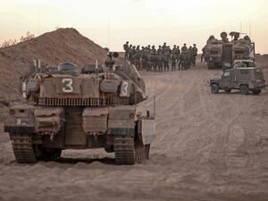 Israeli infantry soldiers gather next to tanks and an armoured personnel carrier near the Israeli border with the Gaza Strip, on August 16, 2020. MENAHEM KAHANA / AFP