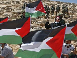 Palestinian landowners and demonstrators lift national flags as they protest Israeli settlement building activities on their land in Al-Thaalaba village, near Yatta in area (C), south of Hebron city in the occupied West Bank, on August 21, 2020. "Area C" is a stretch of land accounting for 60 percent of the West Bank over which Israel has control under the terms of the Oslo Accords signed between Israel and the Palestinians in the 1990s. It is extremely difficult for Palestinians to receive building permits