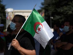 A man wearing a protective mask holds an Algerian flag during a demonstration in front of the United Nations Offices in Geneva against "arbitrary arrests" in Algeria, on August 23, 2020. Fabrice COFFRINI / AFP