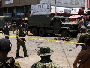 The bodies of victims (C) lie on the pavement as police and military personnel cordon off the site where an improvised bomb exploded next to a military vehicle in the town of Jolo on Sulu island on August 24, 2020. (AFP/File)