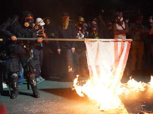 A protester burns an American flag in front of the Mark O. Hatfield U.S. Courthouse in the early morning on August 1, 2020 in Portland, Oregon. Friday was the second night in a row without police intervention, following weeks of clashes between federal officers and protesters in Portland. Nathan Howard/Getty Images/AFP