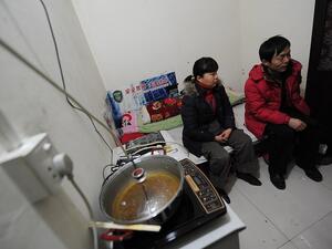 Chinese migrant worker Li Youhong (right) sitting with his wife Qi Shulai in their tiny room, three storeys down in a dimly lit civil defence shelter (AFP)