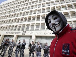 A demonstrator looks on as Lebanese policemen stand guard outside the Central Bank in Beirut last year (AFP)