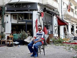 An injured man sits outside a restaurant in the Mar Mikhael area of Lebanon. The port blast ripped through blocks of the city for miles around. (Patrick Baz/AFP/Getty)