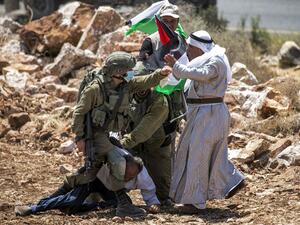 An Israeli soldier, mask-clad due to the COVID-19 coronavirus pandemic, scuffles with Palestinian protesters near the village of Shoufah, southeast of Tulkarm in the occupied West Bank on August 20, 2020, amidst a protest against the clearing of lands to expand Israeli settlements. JAAFAR ASHTIYEH / AFP